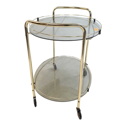 674 - A contemporary brass and smoked glass drinks / hostess trolley in the Art Deco style. Having gilt tu... 