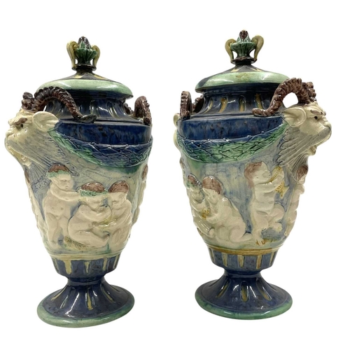 159 - A pair of late 19th century hand painted Majolica grotesque lidded urns. Each vase having a shaped l... 