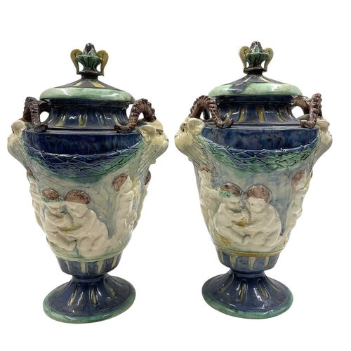 159 - A pair of late 19th century hand painted Majolica grotesque lidded urns. Each vase having a shaped l... 