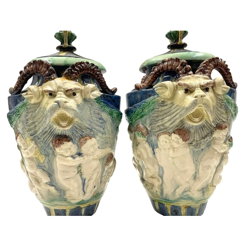 159 - A pair of late 19th century hand painted Majolica grotesque lidded urns. Each vase having a shaped l... 