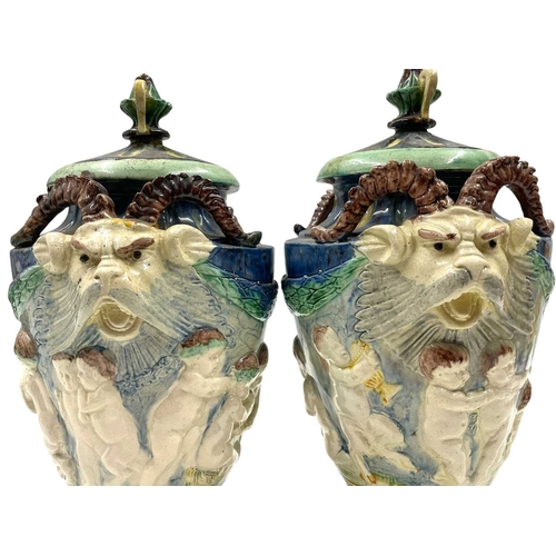 159 - A pair of late 19th century hand painted Majolica grotesque lidded urns. Each vase having a shaped l... 