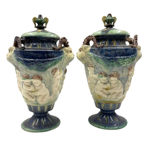 159 - A pair of late 19th century hand painted Majolica grotesque lidded urns. Each vase having a shaped l... 