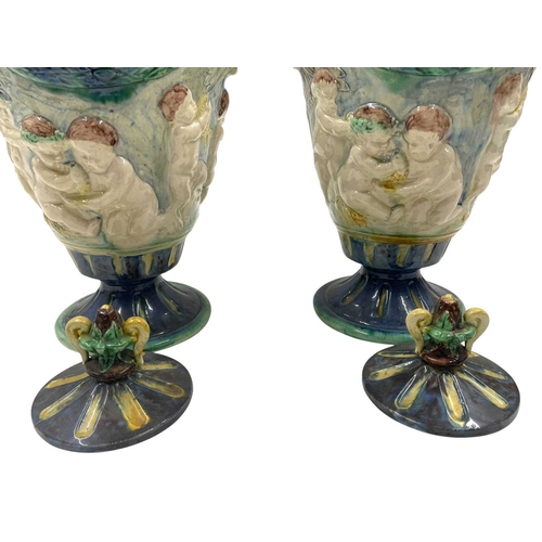 159 - A pair of late 19th century hand painted Majolica grotesque lidded urns. Each vase having a shaped l... 